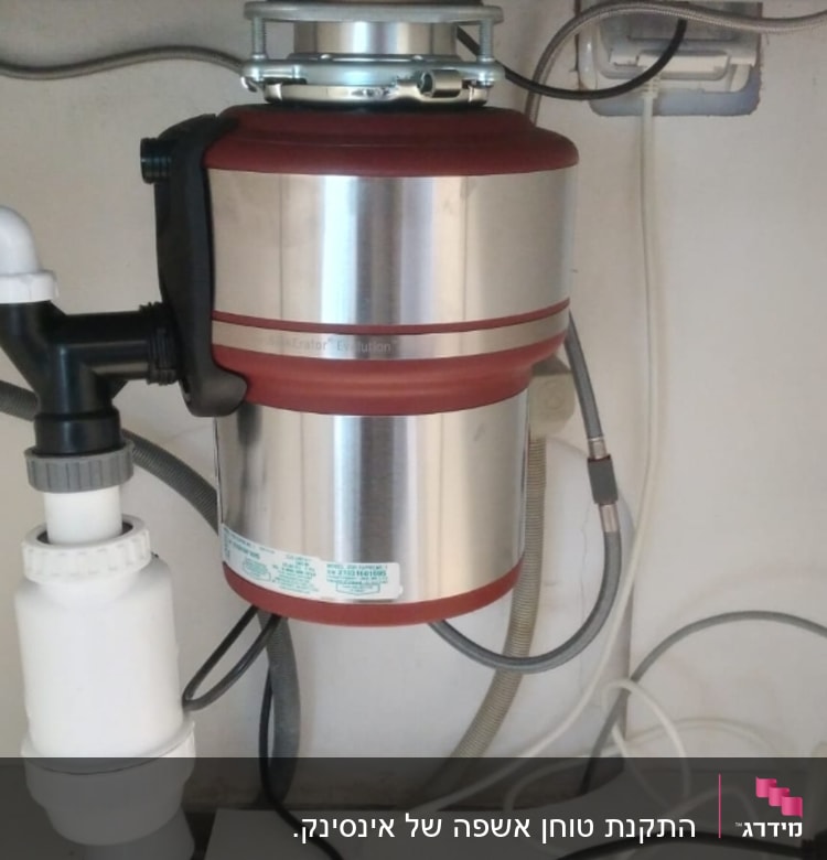 מכשיר טוחן אשפה מתחת לכיור עם צינורות חיבור